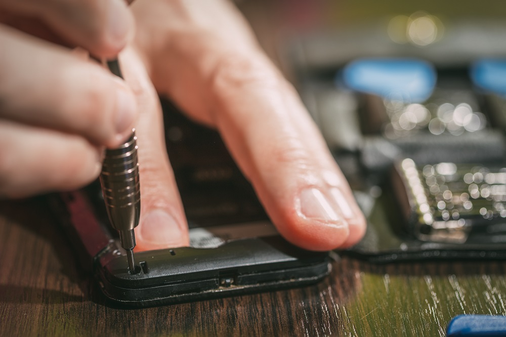 Close-up of a male hands servising broken smartphone.